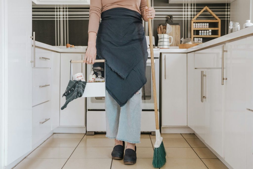 eine Frau steht in einer Küche und hält einen Besen